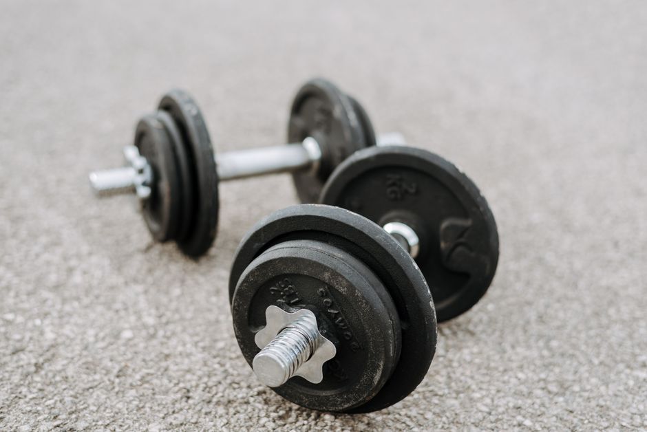 Massive metal dumbbells prepared for difficult healthy training on asphalt road in summer